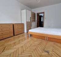 Schlafzimmer in einer 2-Zimmer-Wohnung mit Bett, Kommoden und Holzboden.