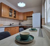 Küche mit Holzschränken und Esstisch in einer 2-Zimmer-Wohnung.