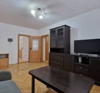 Wohnzimmer mit dunklen Möbeln und Holzboden in einer Zweizimmerwohnung.