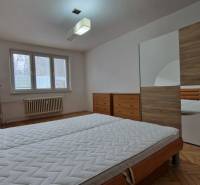 Schlafzimmer mit Bett, Einbauschrank und Boden mit Holzdekor in einer 2-Zimmer-Wohnung.