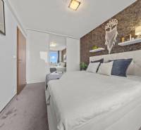 Schlafzimmer in einer 2-Zimmer-Wohnung mit Doppelbett, Spiegelschrank und Wanddekorationen.