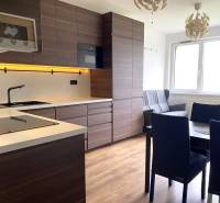 Küche in einer 3-Zimmer-Wohnung mit dunklen Möbeln und einem Boden in Holzoptik.