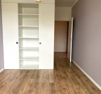 Ein Zimmer mit einem weißen Regal und einem Boden in Holzoptik in einer 3-Zimmer-Wohnung.