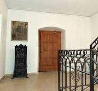 Flur im Büro mit Gemälde, Holztüren und Kachelofen.