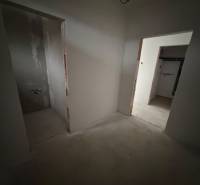 Innenraum eines Einfamilienhauses mit zwei unverputzten Räumen und unfertigem Boden.