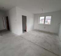 Innenraum eines Einfamilienhauses mit weißen Wänden und Betonboden, großes Fenster.