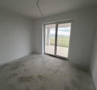 Ein Zimmer in einem Einfamilienhaus mit grauem Boden und großen Fenstern zum Hof.