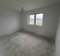 Ein leerer Raum mit einem großen Fenster und einem unfertigen Boden in einem Einfamilienhaus.