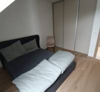Schlafzimmer in einer 2-Zimmer-Wohnung mit Bett und Kleiderschrank, Boden mit Holzdekor.