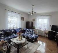 Ein Einfamilienhaus mit einem Sofa, einem Schrank, einem Fernseher, Dekorationen und einem Boden mit Holzdekor.