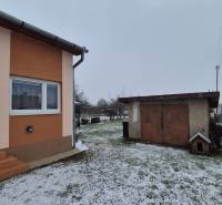 Ein Einfamilienhaus in der Neuen Straße in Veľké Ozorovce mit einem verschneiten Garten und einer Garage.