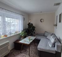 Wohnzimmer in einem Einfamilienhaus mit Sofa, Tisch und Fenster mit Vorhang.