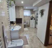 Ein Badezimmer in einem Einfamilienhaus mit einer gefliesten Wand, einem Bidet, einer Waschmaschine und Dekorationen.