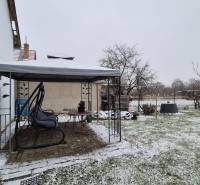 Ein verschneiter Garten bei einem Einfamilienhaus in der Neuen Straße in Veľké Ozorovce mit einem Pavillon.