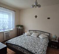 Schlafzimmer im Einfamilienhaus mit gemustertem Überwurf, Fernseher und Boden mit Holzdekor.