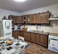 Küche in einem Einfamilienhaus mit Küchenzeile, Esstisch und Boden in Holzoptik.