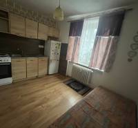 Küchenzeile mit Holzdekor in einer Einzimmerwohnung, inklusive Herd und Kühlschrank.