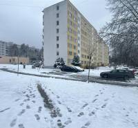 Winterszene in der Bazovského-Straße in Zvolen mit einem Plattenbau und geparkten Autos.
