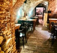 Steinbögen, Holztische und ein Boden mit Holzdekor in Gastronomiebereichen.