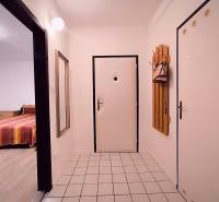 Der Flur in einer 2-Zimmer-Wohnung mit weißen Wänden, Fliesenboden und einem Spiegel.