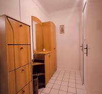 Der Flur in einer 2-Zimmer-Wohnung mit Fliesenboden und Holzmöbeln.