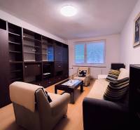 Wohnzimmer mit Sofa, Sesseln, Couchtisch und Wohnwand in einer Zweizimmerwohnung.