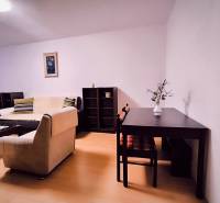 Wohnzimmer in einer Zweizimmerwohnung mit Holzboden, hellem Sofa, Tisch.