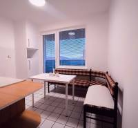 Küche mit Eckbank, Tisch und Fenster in einer 2-Zimmer-Wohnung.