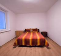 Schlafzimmer in einer 2-Zimmer-Wohnung mit Bett, Nachttisch und Boden in Holzoptik.
