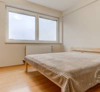 Schlafzimmer in einer 2-Zimmer-Wohnung mit einem Doppelbett und einem Boden in Holzoptik.