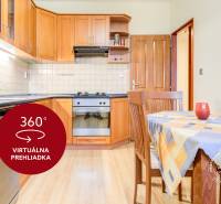 Küche in einer 2-Zimmer-Wohnung mit Arbeitsplatte, Esstisch und Boden in Holzoptik.