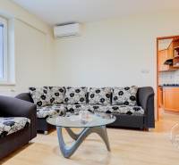 Wohnzimmer in einer Zweizimmerwohnung mit Sofa und Glastisch, Boden mit Holzdekor.