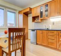 Küche mit Holzschränken, Esstisch und Boden mit Holzdekor in einer Zweizimmerwohnung.