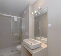 Badezimmer in einer Ferienwohnung mit Waschbecken, Duschkabine und großem Spiegel.