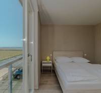 Schlafzimmer im Ferienapartment mit Aussicht, Bett und Boden in Holzoptik.