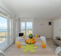 Esstisch im Ferienapartment mit Meerblick durch große Fenster.