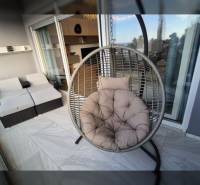 Entspannungsterrasse des Ferienapartments mit rundem Hängesessel und Rattansitzgruppe.