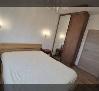 Ferienwohnung mit bequemem Bett und Holzboden, beleuchtet von Wandleuchten.