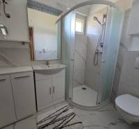 Badezimmer in einer Ferienwohnung mit moderner Duschkabine und weißen Möbeln.