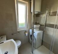 Badezimmer in einem Einfamilienhaus mit Dusche, Waschmaschine und Fenster.