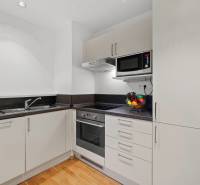 Küche in einer 2-Zimmer-Wohnung mit weißen Schränken und einem Boden in Holzoptik.