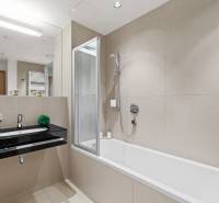 Badezimmer mit Badewanne, schwarzem Waschbecken und Spiegel in einer 2-Zimmer-Wohnung.