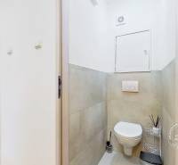 Toilette im Inneren einer 3-Zimmer-Wohnung mit Keramikfliesen und Stauraum.