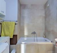 Badezimmer mit Badewanne, Stauraum und farbigen Accessoires in einer 3-Zimmer-Wohnung.