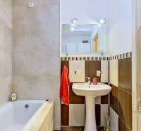 Badezimmer in einer 3-Zimmer-Wohnung mit Badewanne, Waschbecken und Spiegel.