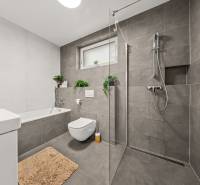Badezimmer in einer 4-Zimmer-Wohnung mit Badewanne, Dusche und Toilette, graue Fliesen.