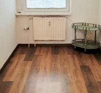 Ein Zimmer mit einem Holzboden und einem grünen Tisch, eine 3-Zimmer-Wohnung.