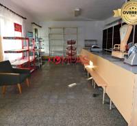 Innenraum eines Geschäftsraums mit Theke, Regalen und Sessel.