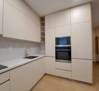 Küche in einer 2-Zimmer-Wohnung mit Holzboden, hellen Schränken und eingebautem Ofen.