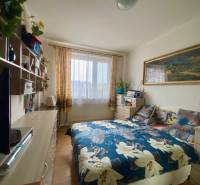 Schlafzimmer mit Bett, Regalen und Boden mit Holzdekor in einer 3-Zimmer-Wohnung.